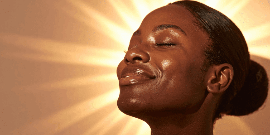 Mulher feliz e confiante com a pele saudável e radiante como resultado de uma rotina de autocuidado.