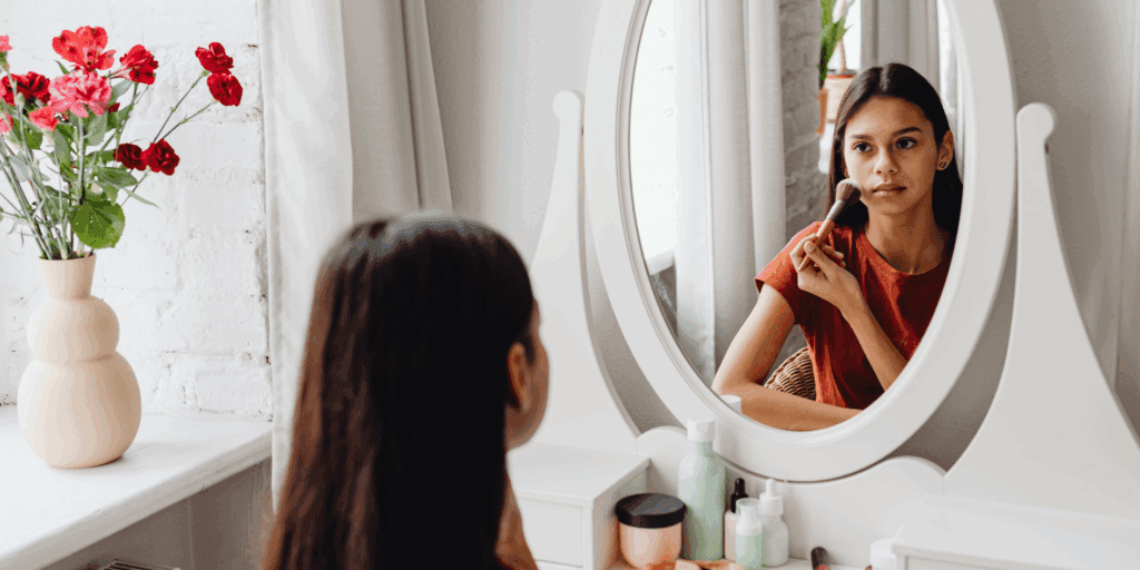 "Mulher iniciante na maquiagem com expressão de dúvida, tentando aplicar produtos no rosto.