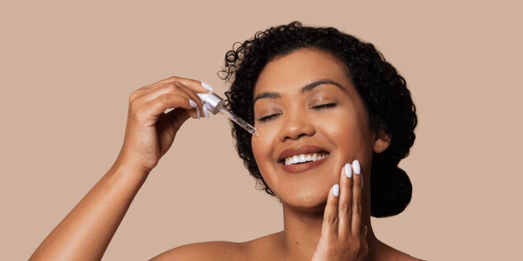 Mulher sorrindo e tocando o rosto, mostrando uma pele saudável e radiante, resultado do uso dos melhores produtos com ácido glicólico e salicílico.