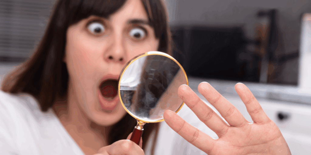 mulher com unhas curtas e frágeis, olhando para elas com preocupação, simbolizando unhas danificadas pós-gel