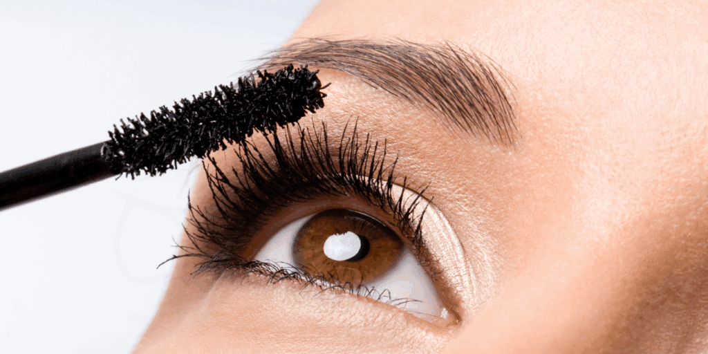  Mulher aplicando máscara de cílios, um passo fundamental na maquiagem para iniciantes.