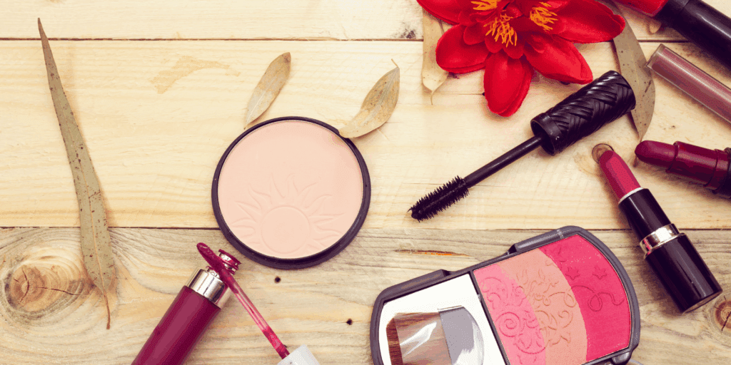 (skin tint, blush cremoso, gloss e máscara de cílios) em uma bancada iluminada.