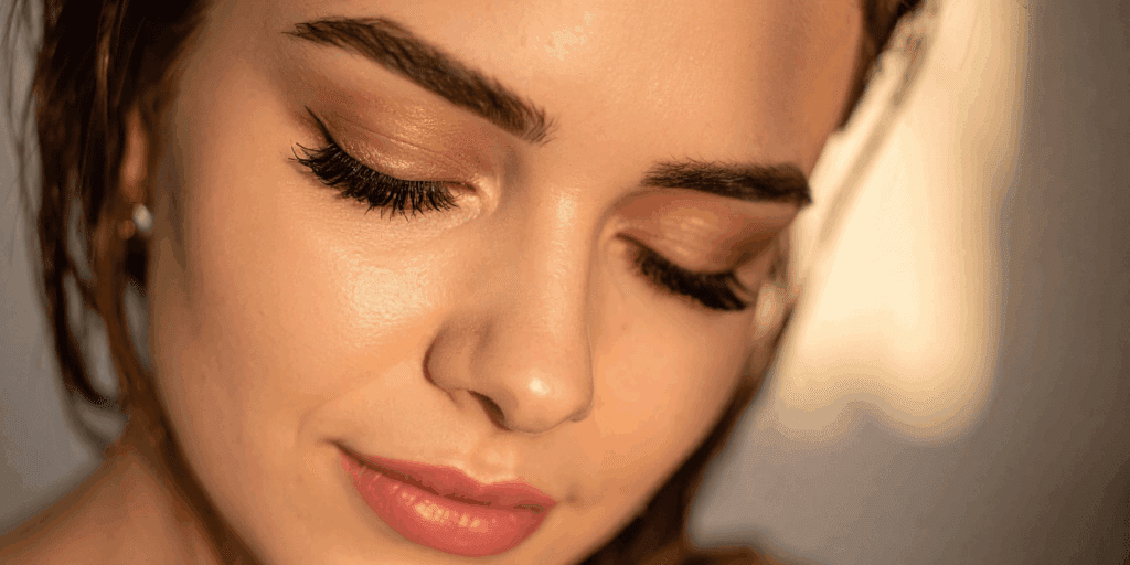 Close-up de uma mulher sorrindo com maquiagem leve e iluminada na primavera, destacando o blush cremoso e o glow natural.