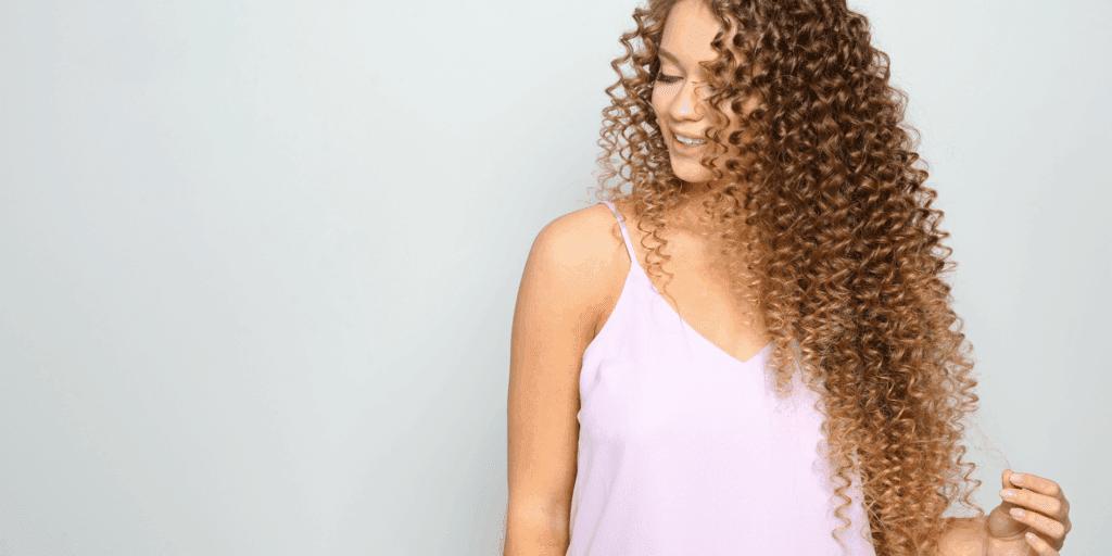 Close-up do cabelo de uma mulher brilhante e sem frizz, refletindo a luz da primavera.