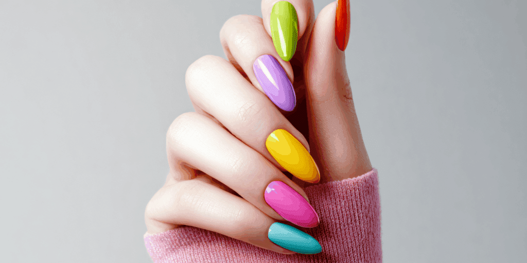 Close-up de mãos de uma mulher com unhas em tom pastel 