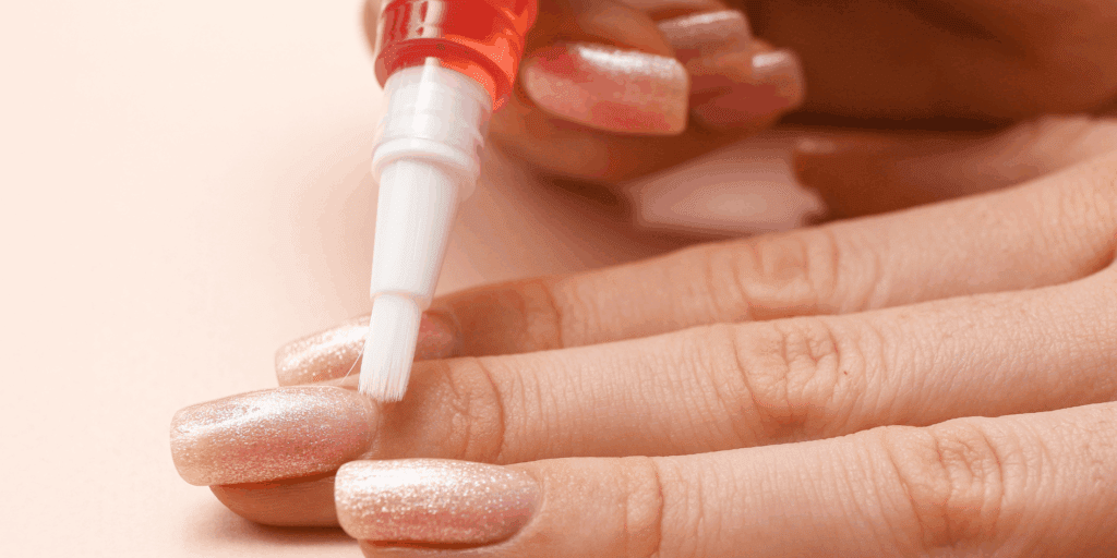 Mulher aplicando óleo fortalecedor nas cutículas como parte da sua rotina de cuidados com as unhas.