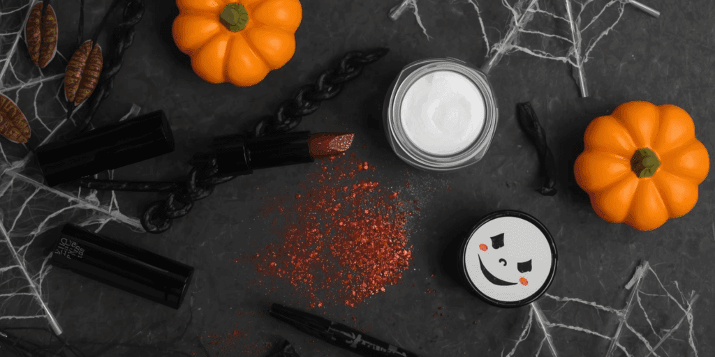 Maquiagem artística para Halloween com produtos essenciais, como tinta facial branca, delineador preto, batom vinho e glitter.