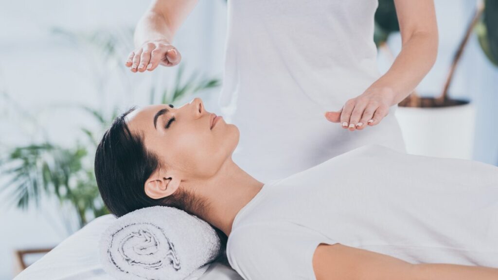 Uma pessoa deitada relaxada (recebendo Reiki), e um par de mãos posicionado suavemente sobre a cabeça ou o peito dela, com uma luz suave ou brilho emanando das mãos. Transmite paz e cura.