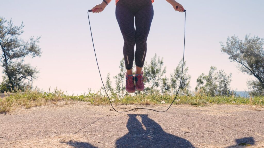 Uma foto dinâmica, focada nos pés (tênis) de alguém pulando corda, com a corda "borrada" pelo movimento rápido. Transmite energia e queima calórica.