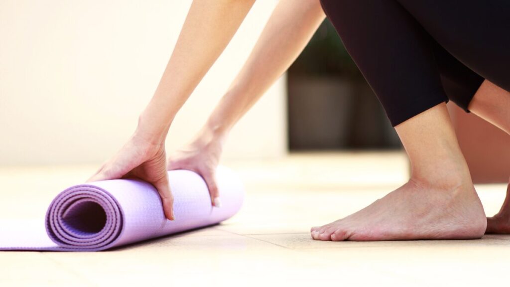 mulher recolhendo seu tapete de yoga