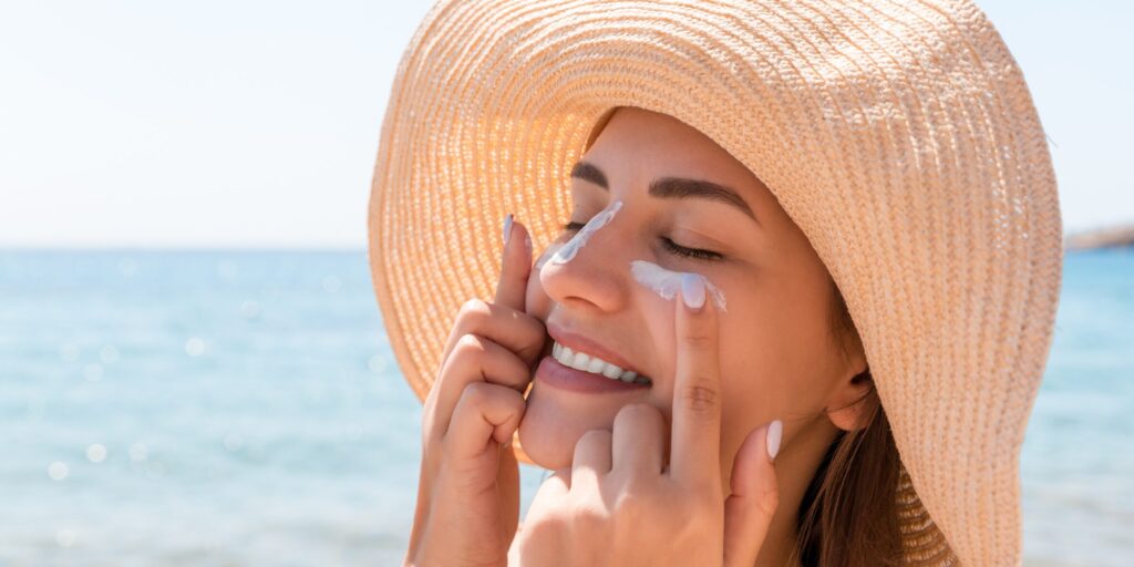 Uma foto de uma mulher na praia  sorrindo. O foco deve ser no "conforto" de usar protetor solar sem se preocupar em "lacrimejar", transmitindo a ideia de verão e proteção sem ardência.